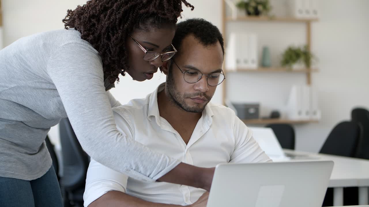Slow motion shot of focused colleagues talking and looking at laptop
