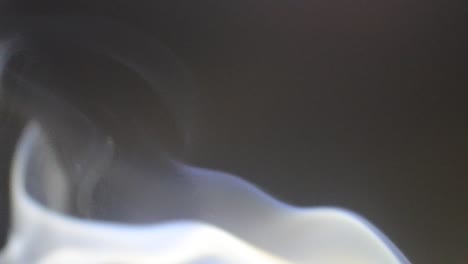 smoke from mosquito coil in slow motion, white smoke slowly floating through space against dark, atmospheric smoke