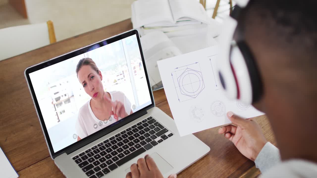 estudiante universitario afroamericano que sostiene notas mientras hace una videollamada en una computadora portátil en casa