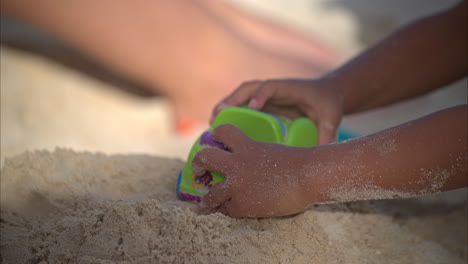 Close-up-of-the-hands-of-a-little-baby-boy-playing-with-a-car-toy-on-the-sand-on-a-sunny-summer-day