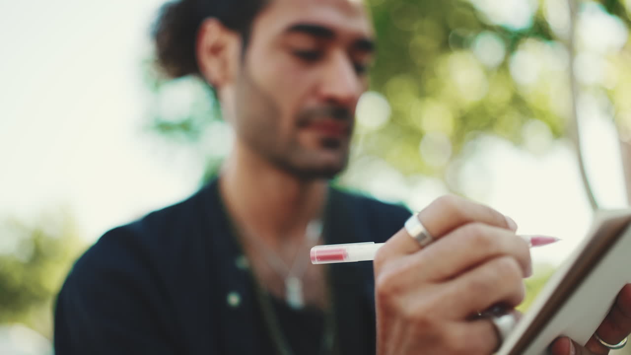Man Writing in Notebook Outdoors