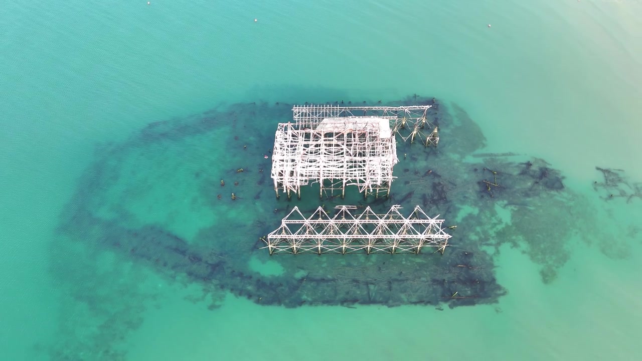 Droneopptak fanger Brightons forlatte West Pier ved rekordlavvann, med skjelettlignende rester og nedsenkede fundamenter som dukker opp fra havet