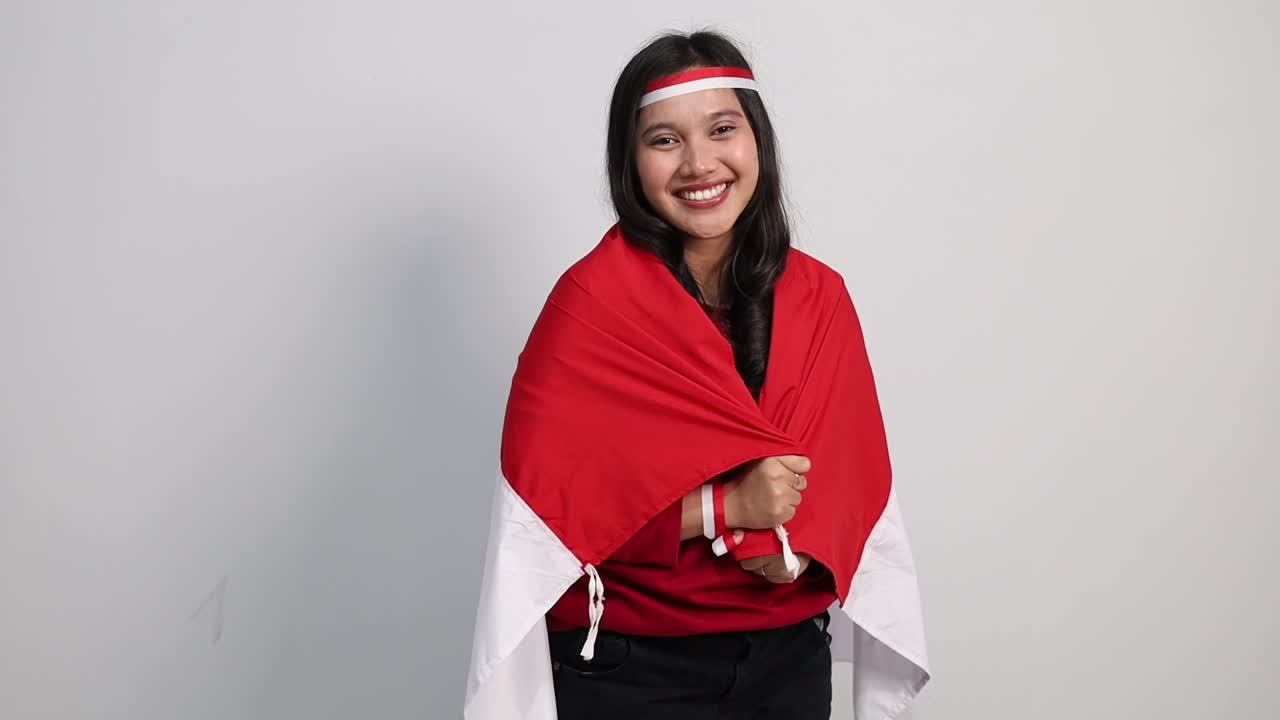 Young Indonesian woman celebrate Indonesian independence day on 17 August by holding the Indonesian flag