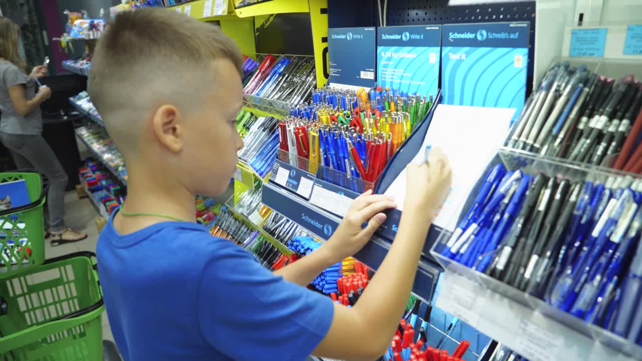 VINNITSA, UKRAINE - AUGUST 20, 2018: Boy selects pens in the stationery store. Buying school supplies at the supermarket