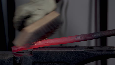 blacksmith brushing red hot metal