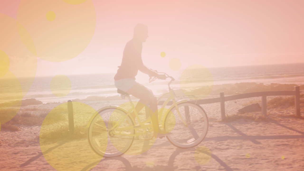 해변에서 자전거를 타는 백인 여성에 대한 빛의 노란색 반점