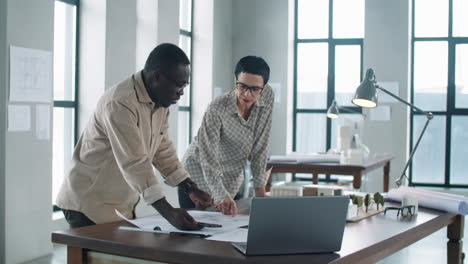 diverse male and female architects discussing construction plan