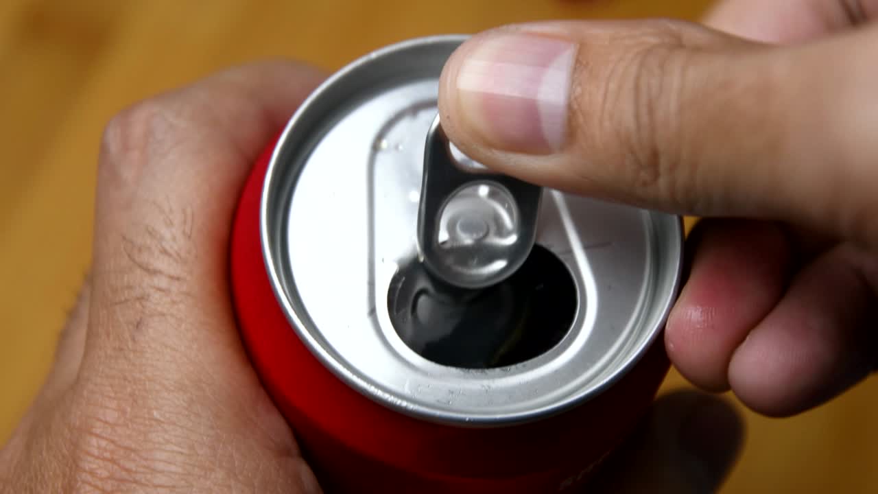 dedos abriendo una lata fría de refresco, bebida gaseosa