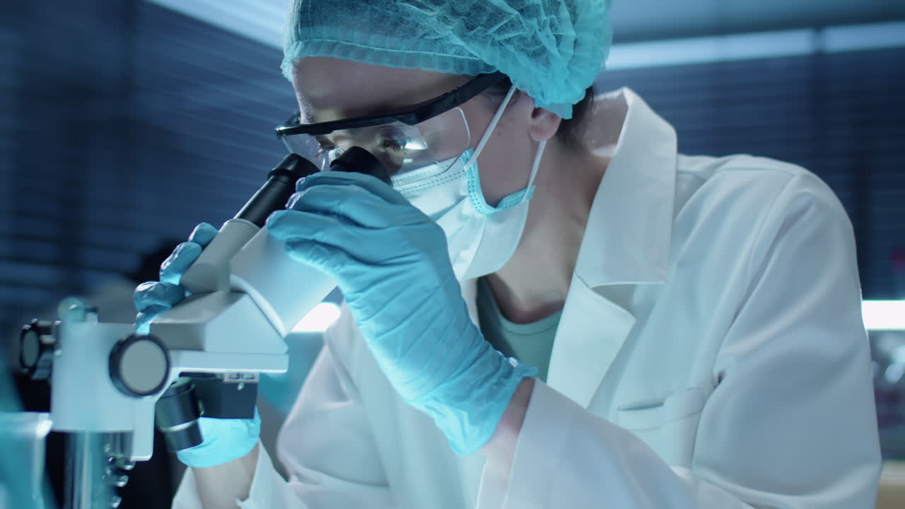 Female Lab Scientist in Mask Using Microscope