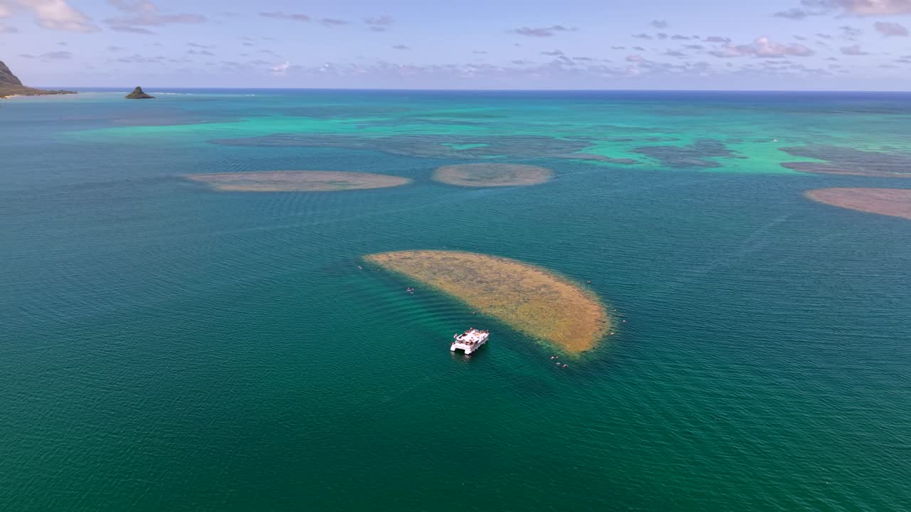 Vast ocean of Kaneohe Bay with coral reefs and Koolau mountains, aerial view