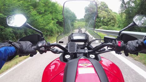 pov biker rides on a motorbike by forested mountain road in italy