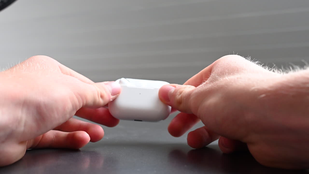 젊은 음악 소비자가 들고 있는 흰색 상자에 이어폰이 보관되어 있습니다.