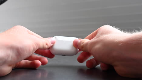 an earphone is stored in a white box, held by a young music consumer