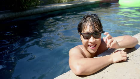 Un-Adolescente-Asiático-Disfruta-De-Un-Día-Soleado-En-La-Piscina,-Con-Espacio-Para-Copiar