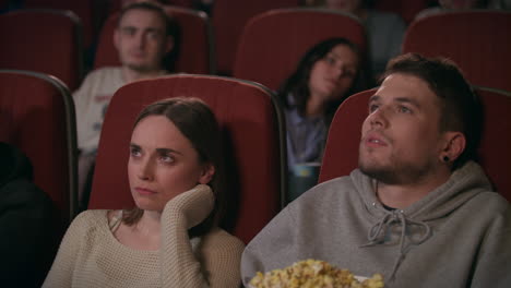 audience watching film in movie theater. couple watching bored movie