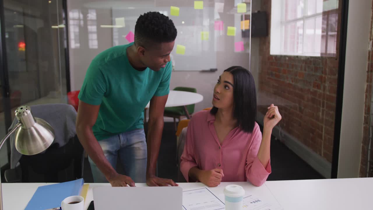 Diverse male and female business colleagues in discussion in meeting room analyzing documents