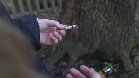 Girl-holding-a-lit-Cigarette-and-lighter-in-a-forest