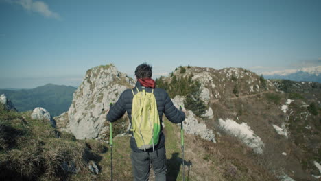 Camera-tracking-hiker-walking-downhill-on-a-narrow-path-on-the-mountain-with-a-clear-beautiful-view-around-the-landscape