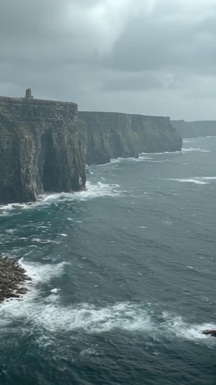 Majestic Coastal Cliffs Overlooking Turbulent Ocean Waters on a Gloomy Day with Dramatic Sky and Churning Waves in the Distance