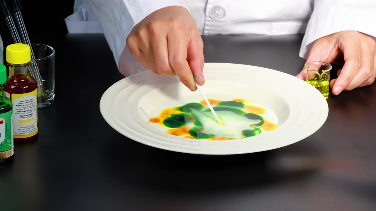 Watch colorful patterns emerge as liquids mix in a shallow dish, creating a mesmerizing visual effect.