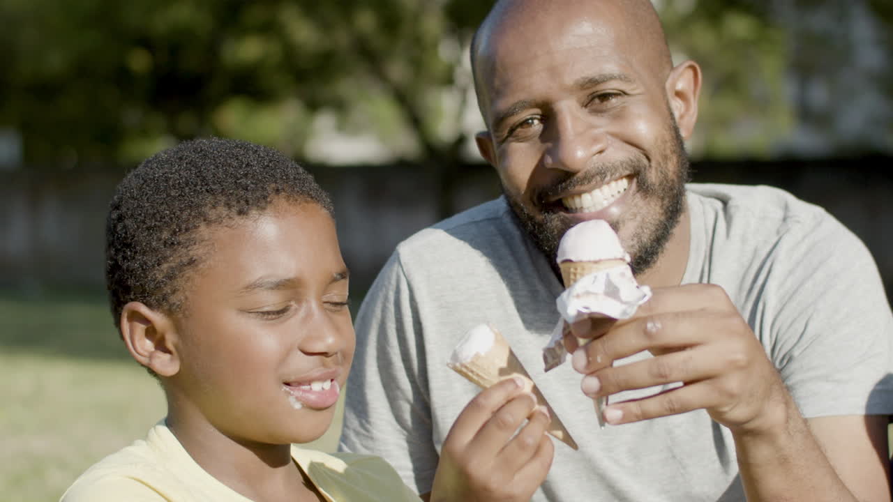 Padre e hijo comiendo helado mientras pasean por un parque
