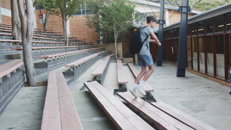 running through school courtyard, boy with backpack jumping over benches, copy space