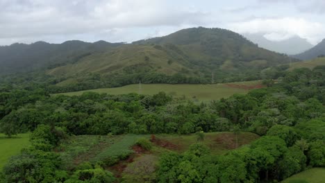 toma aérea lenta a baja altura, campos verdes, nubes, brisa fresca en bonao, república dominicana