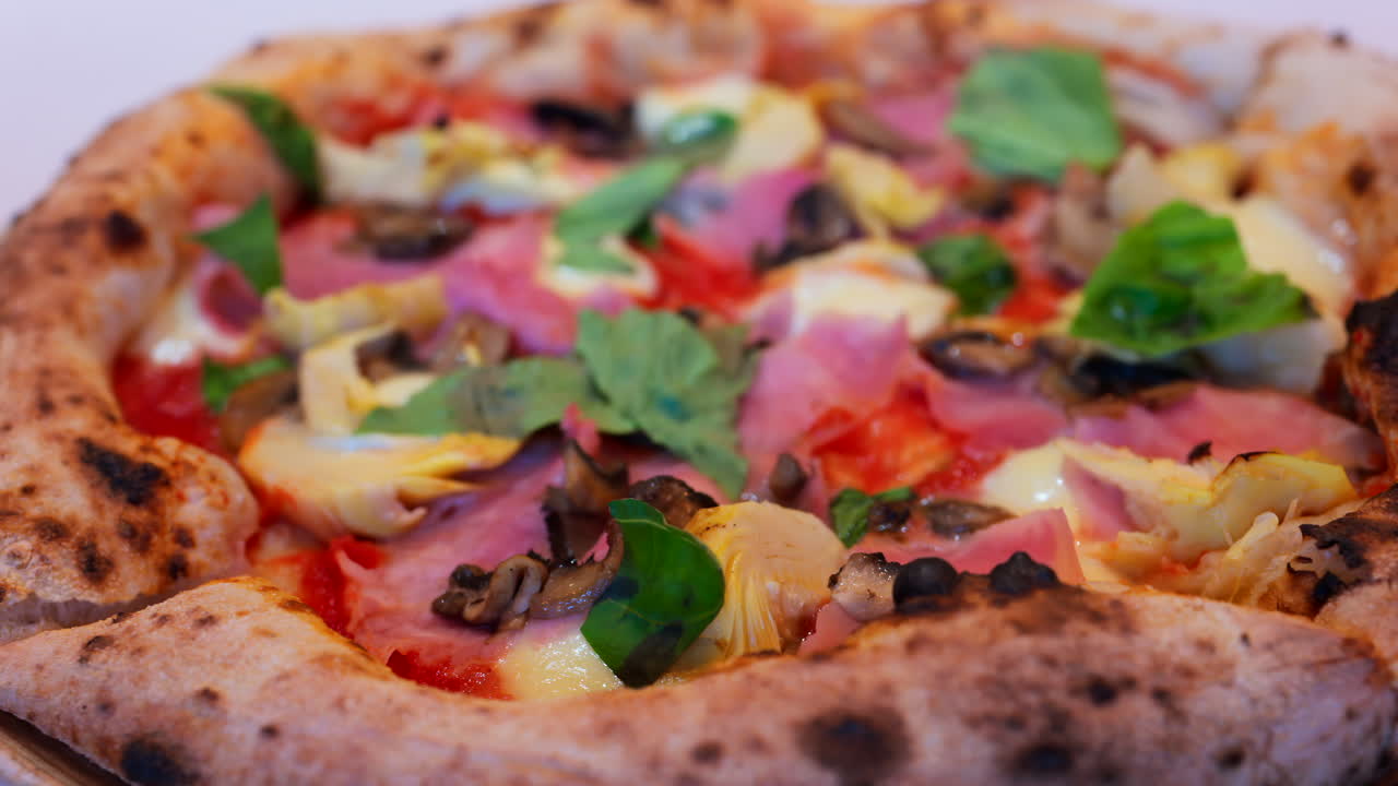 Close up of pizza with artichoke, ham, mushrooms and basil