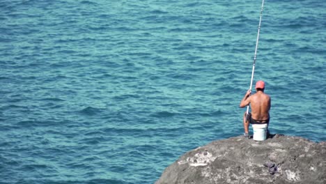 pescador en una roca junto al océano