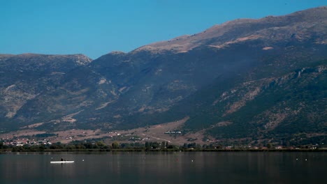 a person is rowing in front of the mountains of the lake of ioannina in greece