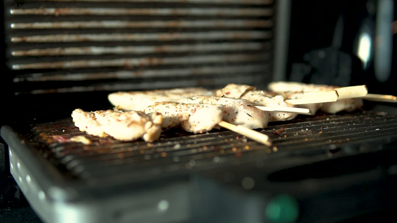 석쇠 위에서 김이 나는 닭고기와 닫힌 석쇠 덮개를 클로즈업하여 보여줘요.