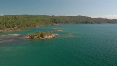 Drone-panning-up-from-sea-to-shore-and-blue-sky-with-windmills