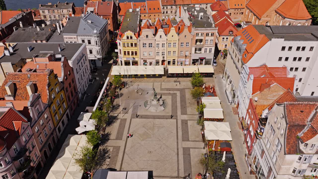 Drone slowly pans left revealing Grudziądz square, monument and birds in flight
