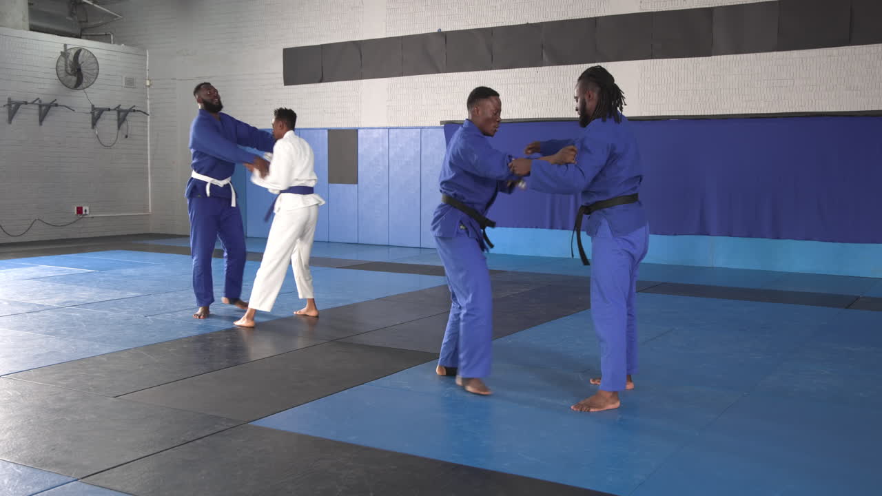 Practicing judo, athletes in martial arts uniforms training in dojo