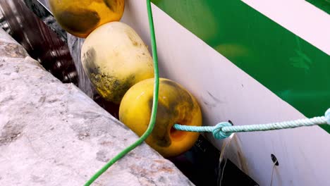 Static close up of a ship's defensive yellow buoys while the ship is draining