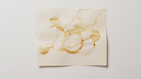 video of close up of piece of paper with round coffee mug stains on white background