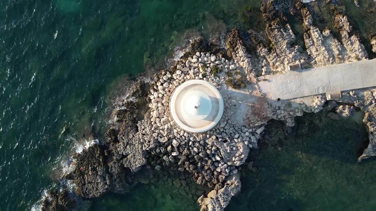 Riprese cinematografiche con drone che mostrano il Faro di San Teodoro e la sua suggestiva cornice costiera.