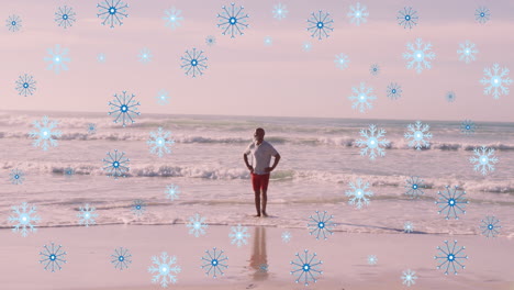 animación de copos de nieve sobre un anciano afroamericano en la playa.
