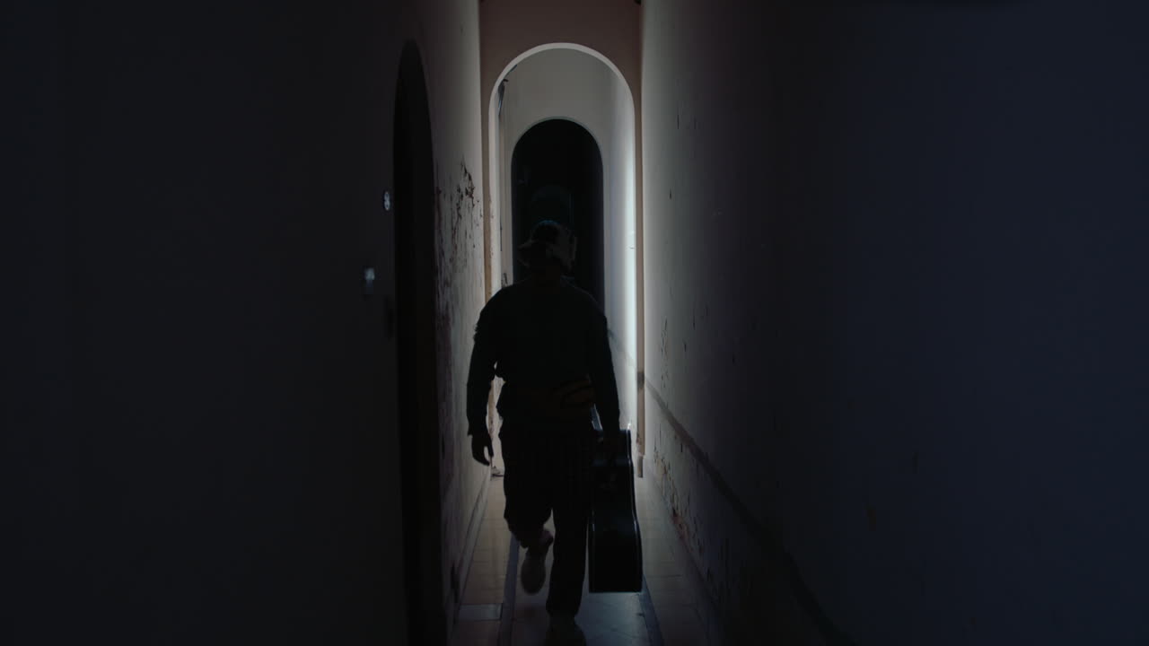 Musician with Guitar Walking through Corridor