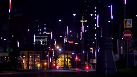 city street at night with colorful illuminated poles