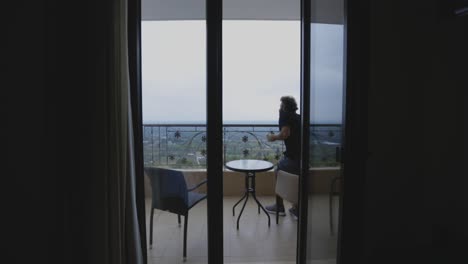 Man-drinking-coffee-on-a-hotel-balcony