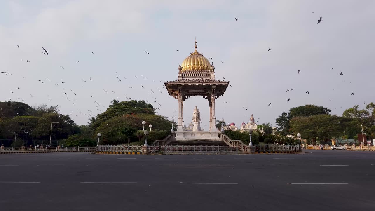 Et daggrysbillede af Maharaja Memorial-cirklen og kredsende duer uden for Mysuru Royal Palace i Mysuru, Indien i 4k-opløsning