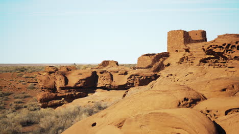 still shot with red sandstone rock formations in foreground and wukoki pueblo ruins in background