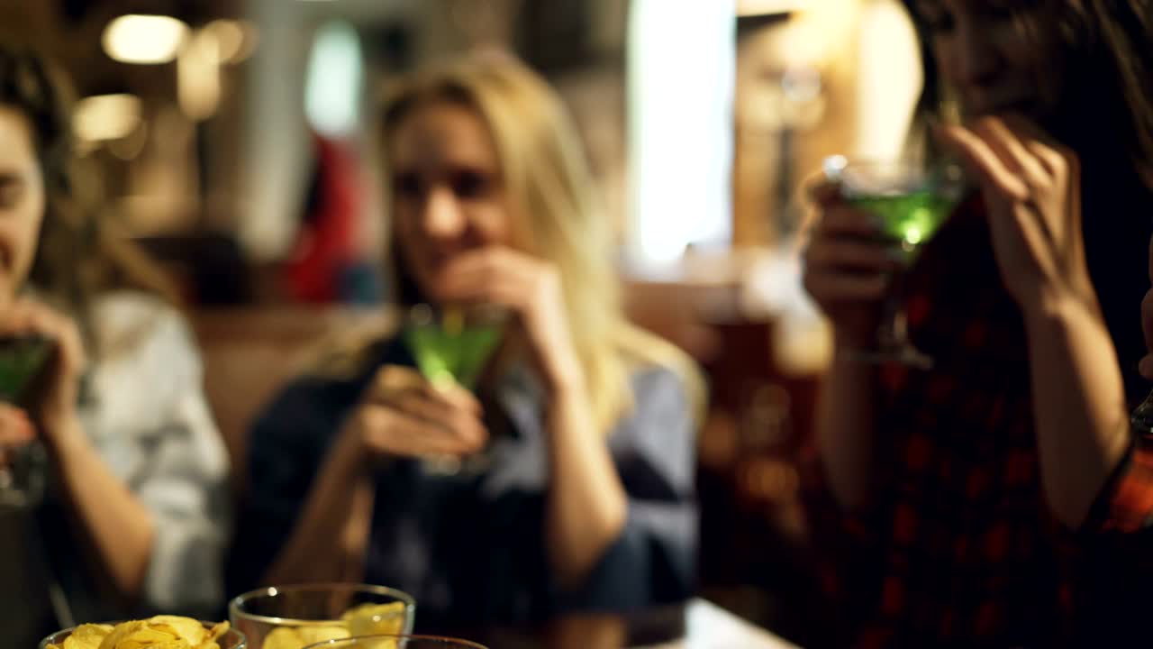 un primer plano de manos masculinas y femeninas sosteniendo copas de cerveza y cócteles y haciendo sonarlas. rostros de hombres y mujeres jóvenes en el fondo, centrarse en los vasos.