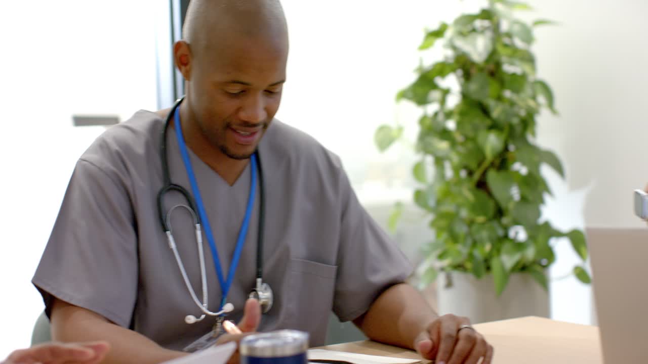 Des membres du personnel médical afro-américain en uniforme réagissent à l'arrivée d'un homme à la clinique, consultant un ordinateur portable et discutant.