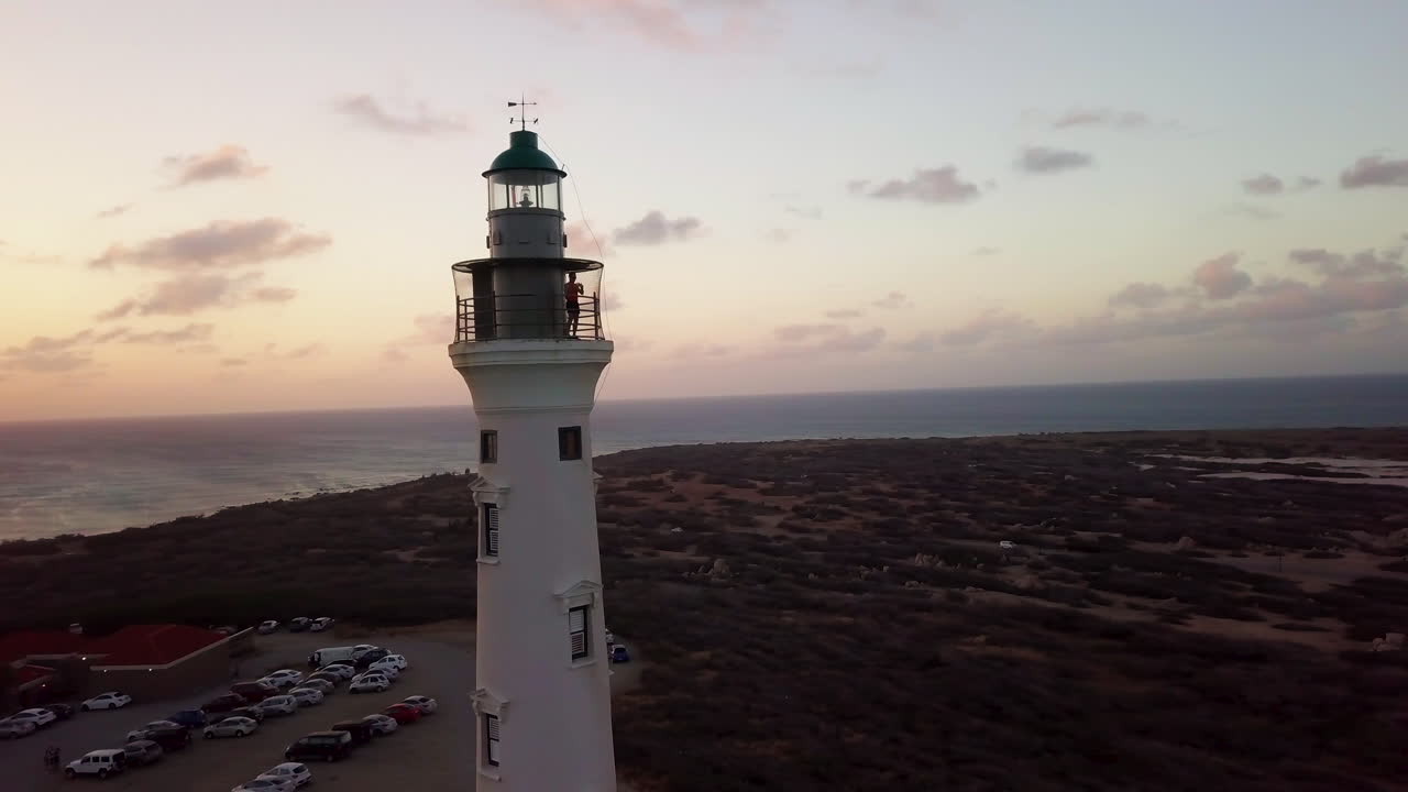 un hombre toma fotos de aruba desde lo alto del faro de california durante una hermosa puesta de sol naranja