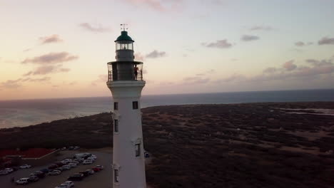 a man takes photos of aruba from the top of the california lighthouse during a beautiful orange sunset