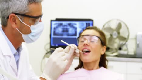 dentista examinando a una paciente femenina con herramientas