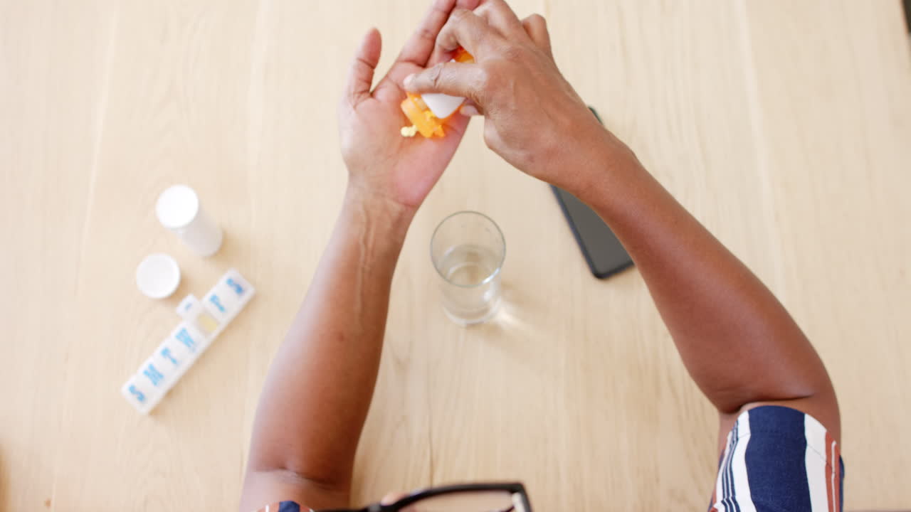 A senior African American woman is opening pill bottle