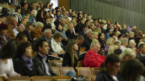 crowd of people to sitting and listening in a large hall